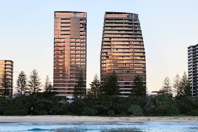 Mondrian Gold Coast twin residential towers at dusk above the beach and pine trees